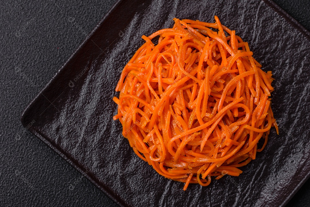 Saborosa cenoura coreana picante com especiarias e ervas em um fundo escuro de concreto. comida asiática