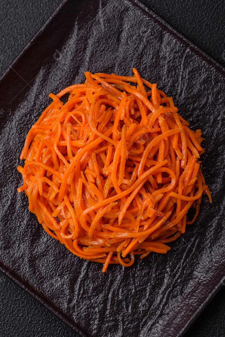 Saborosa cenoura coreana picante com especiarias e ervas em um fundo escuro de concreto. comida asiática