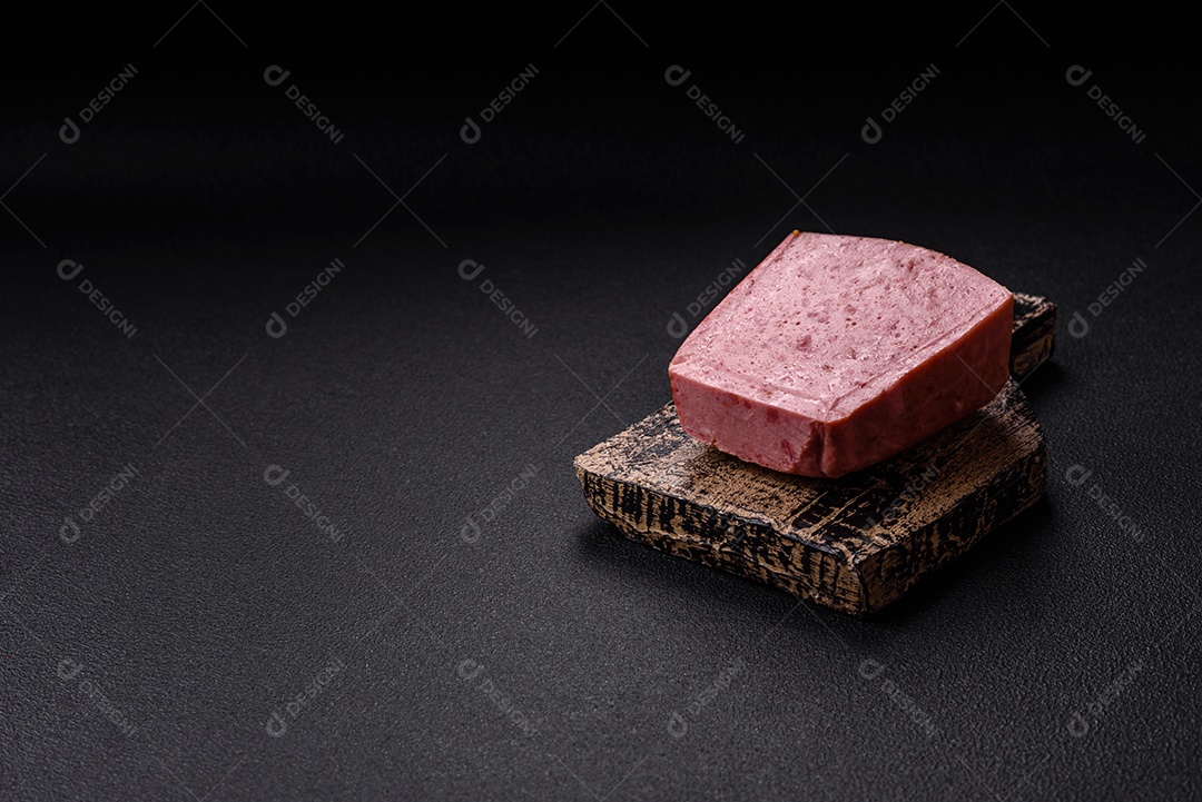 Delicioso presunto rosa enlatado com sal, especiarias e ervas sobre um fundo escuro de concreto