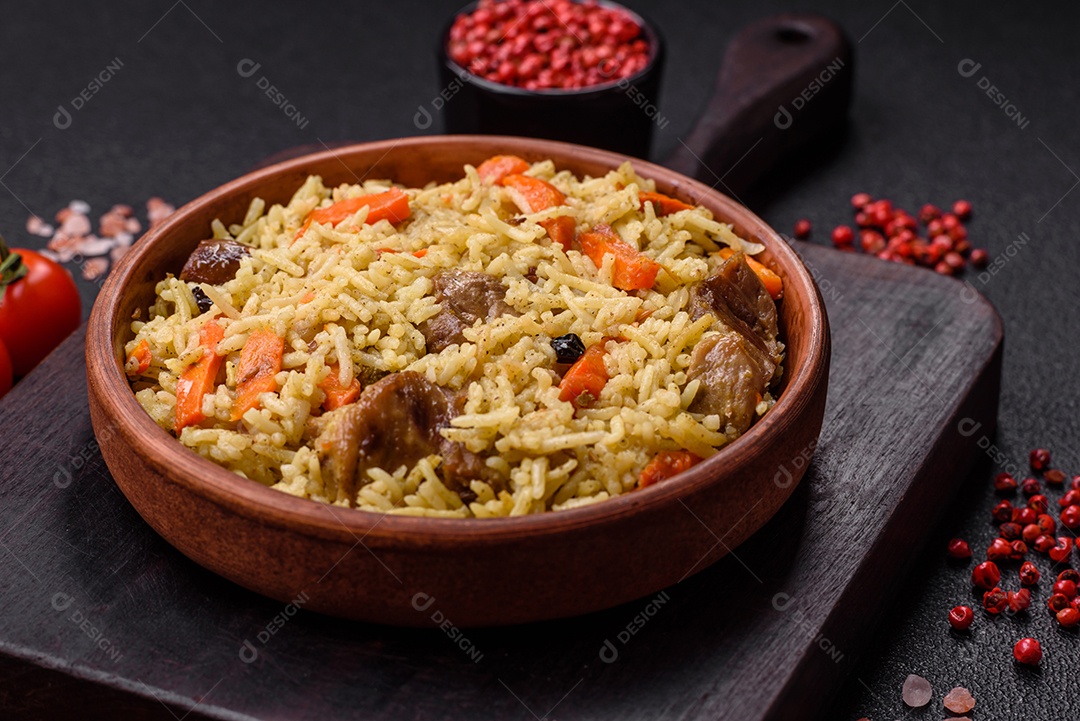 Delicioso pilaf com legumes, sal, especiarias e ervas em uma placa cerâmica sobre um fundo escuro de concreto