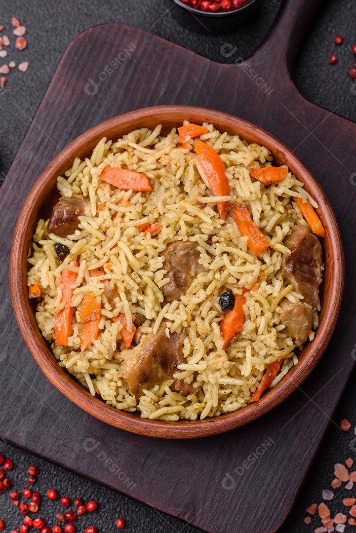 Delicioso pilaf com legumes, sal, especiarias e ervas em uma placa cerâmica sobre um fundo escuro de concreto