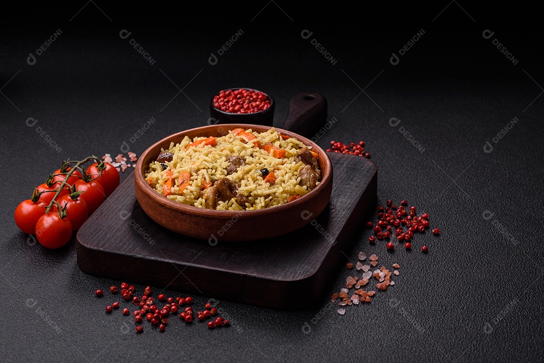 Delicioso pilaf com legumes, sal, especiarias e ervas em uma placa cerâmica sobre um fundo escuro de concreto