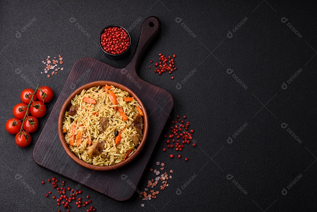 Delicioso pilaf com legumes, sal, especiarias e ervas em uma placa cerâmica sobre um fundo escuro de concreto