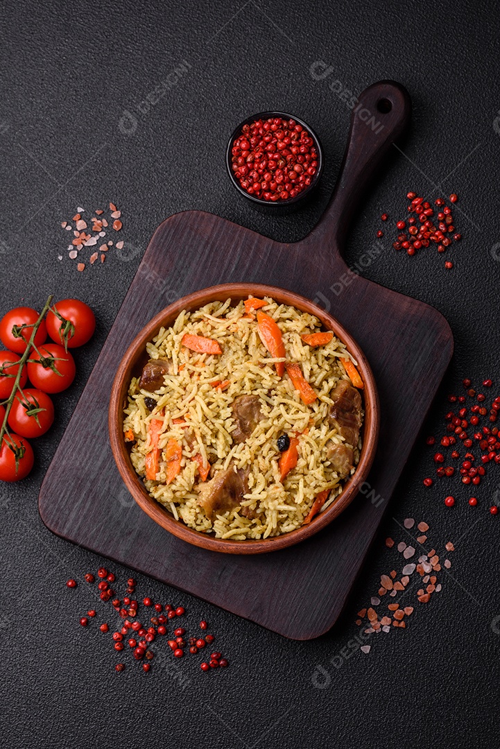 Delicioso pilaf com legumes, sal, especiarias e ervas em uma placa cerâmica sobre um fundo escuro de concreto