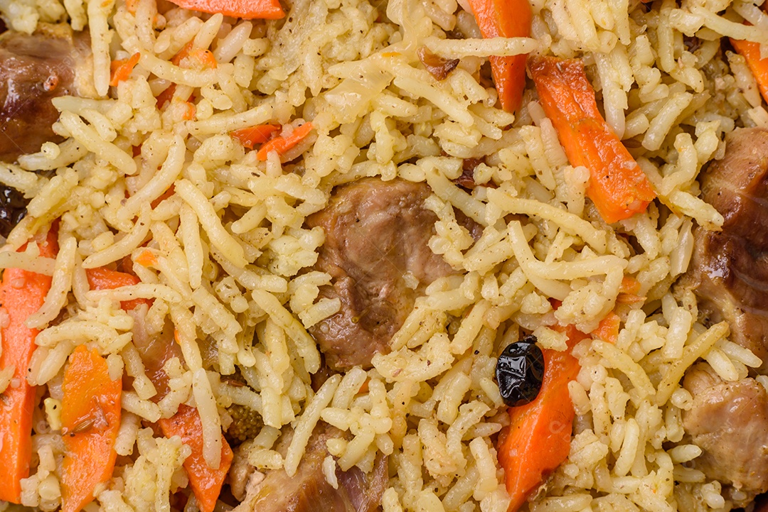 Delicioso pilaf com legumes, sal, especiarias e ervas em uma placa cerâmica sobre um fundo escuro de concreto