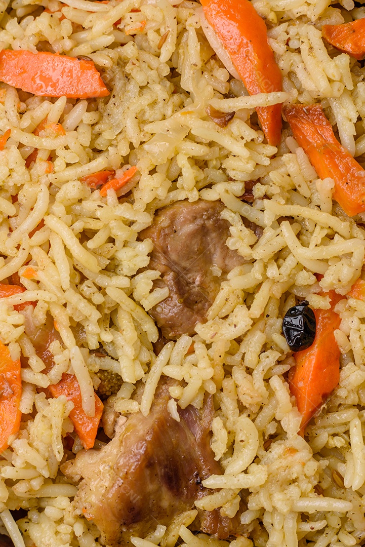 Delicioso pilaf com legumes, sal, especiarias e ervas em uma placa cerâmica sobre um fundo escuro de concreto