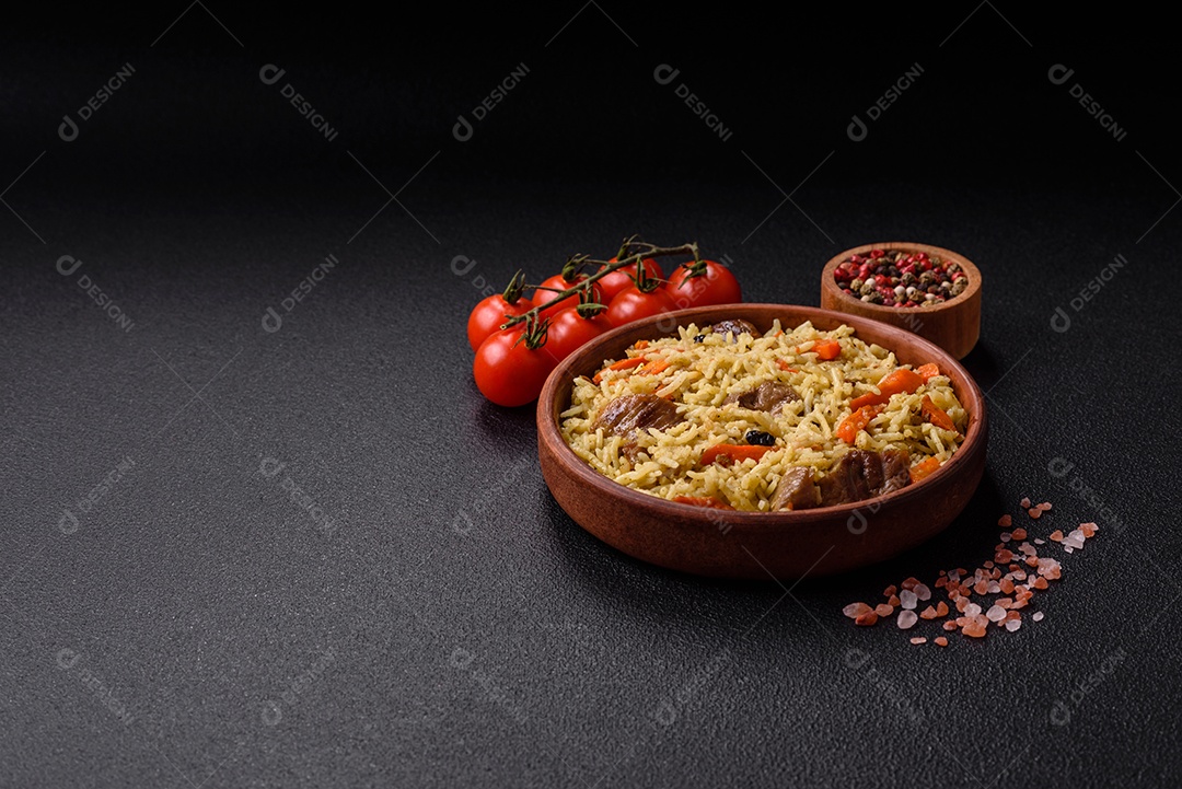 Delicioso pilaf com legumes, sal, especiarias e ervas em uma placa cerâmica sobre um fundo escuro de concreto
