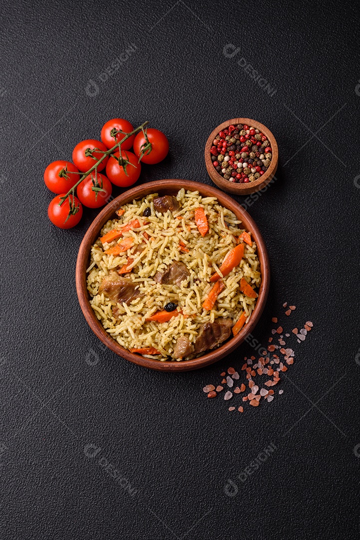 Delicioso pilaf com legumes, sal, especiarias e ervas em uma placa cerâmica sobre um fundo escuro de concreto