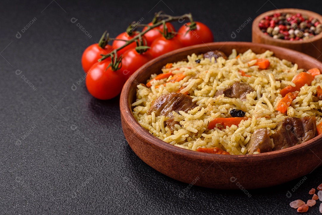 Delicioso pilaf com legumes, sal, especiarias e ervas em uma placa cerâmica sobre um fundo escuro de concreto