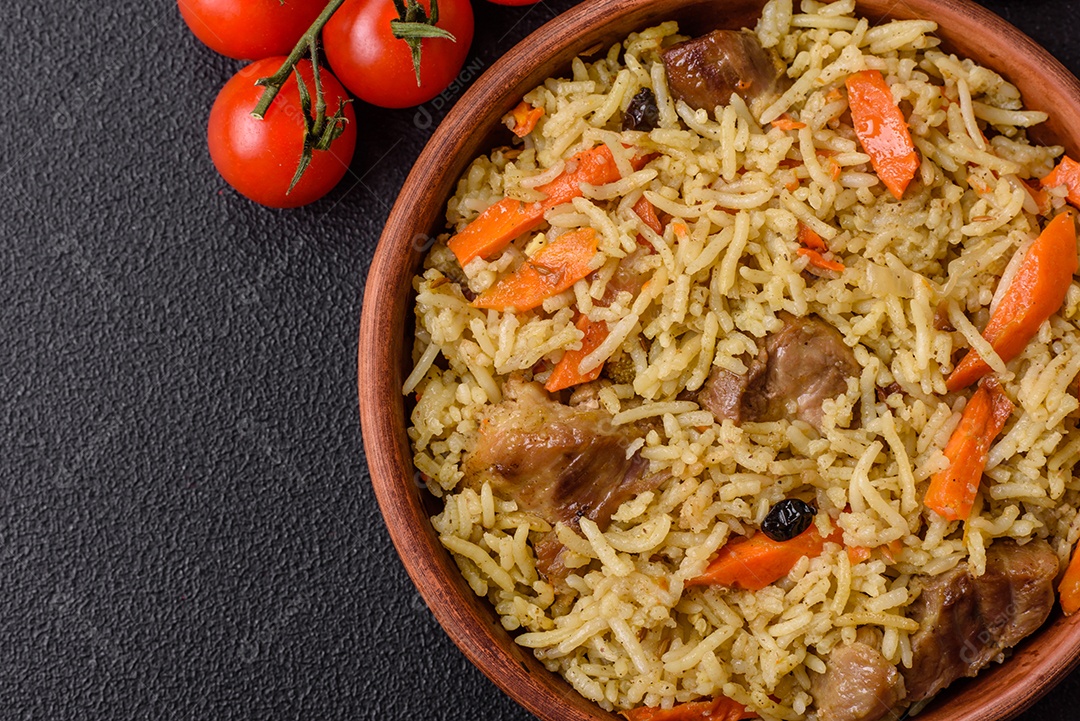 Delicioso pilaf com legumes, sal, especiarias e ervas em uma placa cerâmica sobre um fundo escuro de concreto