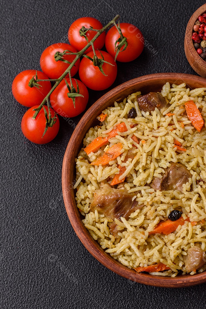 Delicioso pilaf com legumes, sal, especiarias e ervas em uma placa cerâmica sobre um fundo escuro de concreto