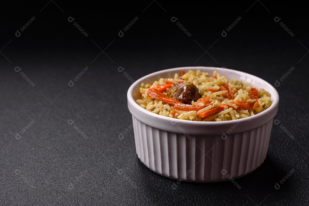 Delicioso pilaf com legumes, sal, especiarias e ervas em uma placa cerâmica sobre um fundo escuro de concreto