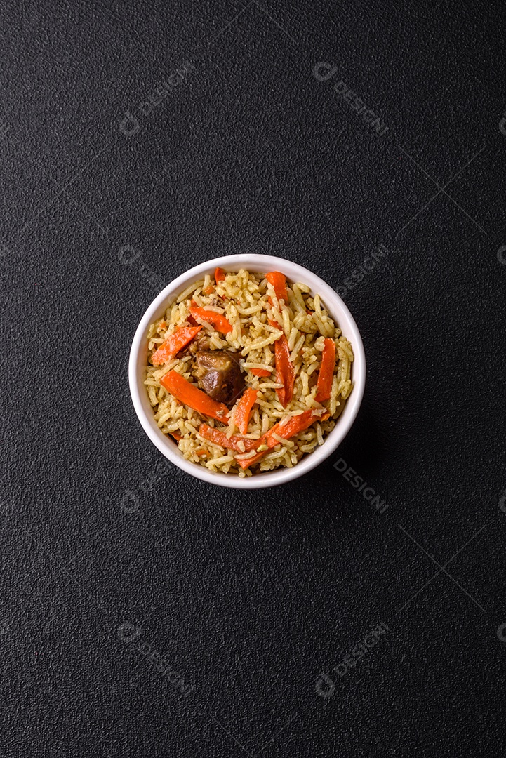 Delicioso pilaf com legumes, sal, especiarias e ervas em uma placa cerâmica sobre um fundo escuro de concreto