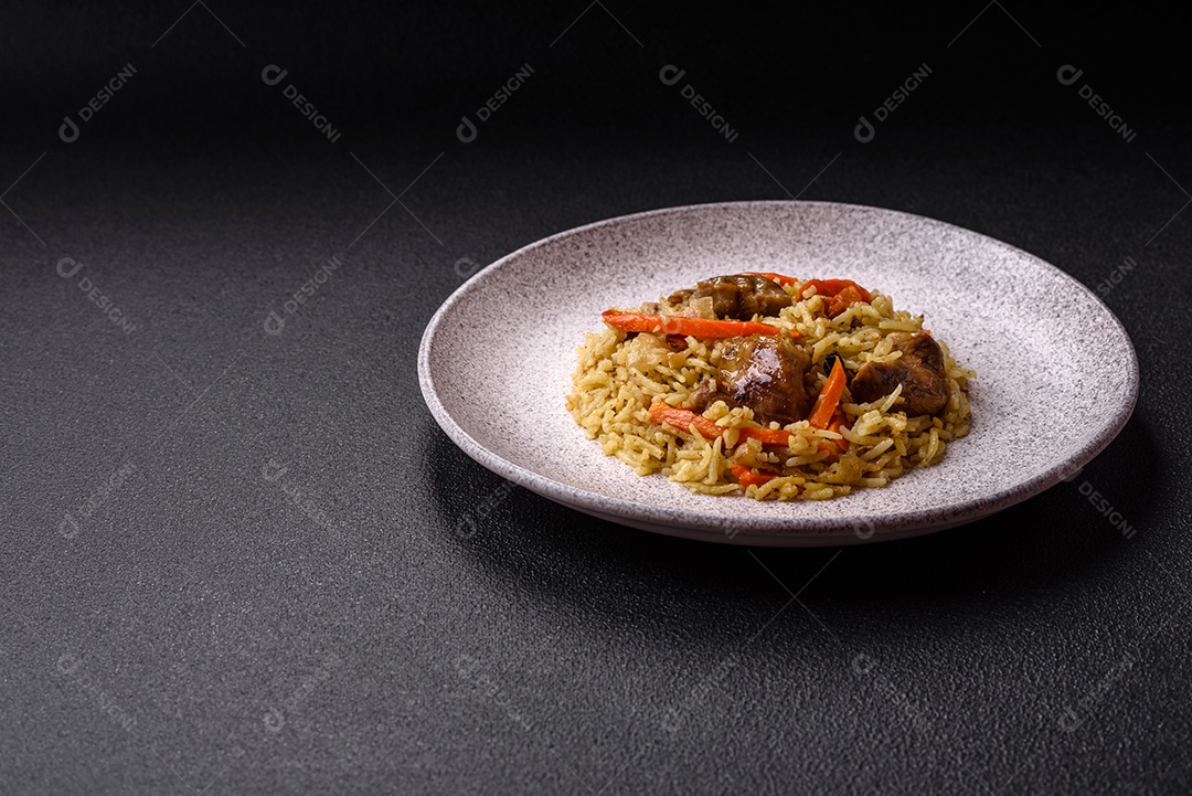 Delicioso pilaf com legumes, sal, especiarias e ervas em uma placa cerâmica sobre um fundo escuro de concreto