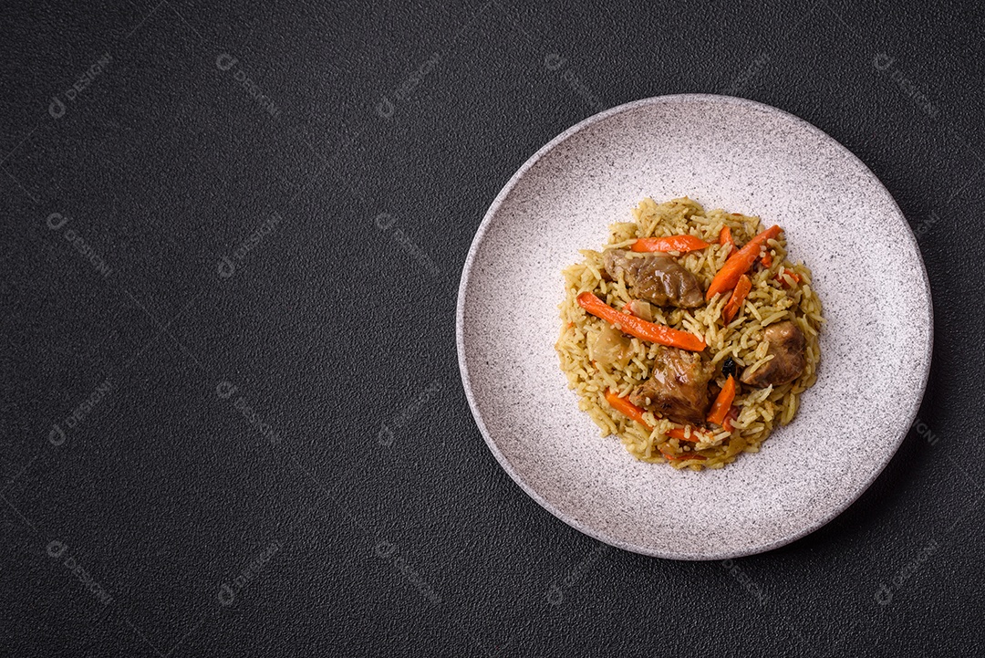 Delicioso pilaf com legumes, sal, especiarias e ervas em uma placa cerâmica sobre um fundo escuro de concreto