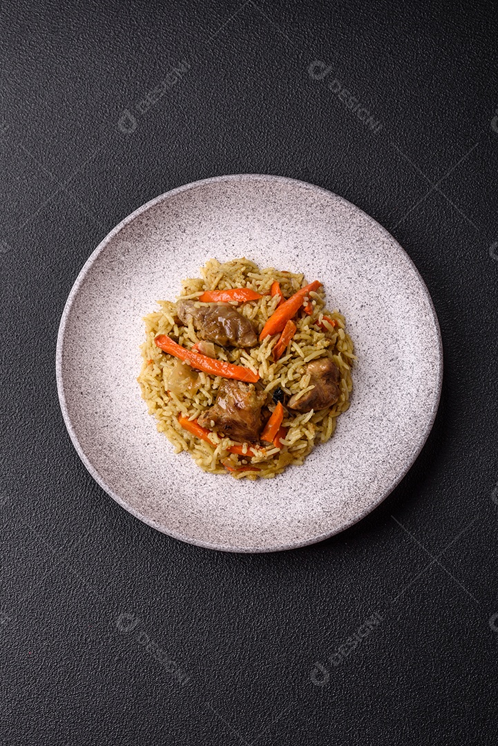 Delicioso pilaf com legumes, sal, especiarias e ervas em uma placa cerâmica sobre um fundo escuro de concreto