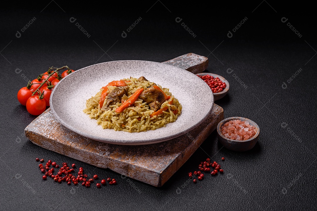 Delicioso pilaf com legumes, sal, especiarias e ervas em uma placa cerâmica sobre um fundo escuro de concreto