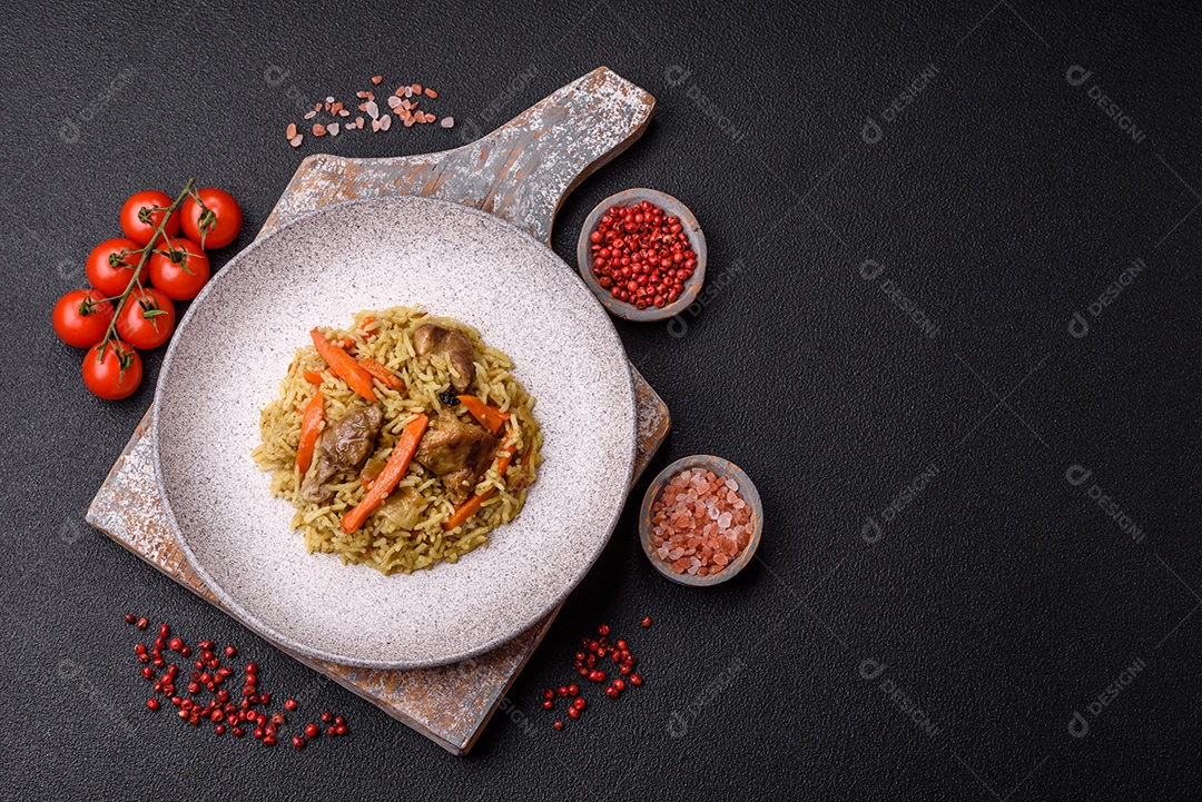 Delicioso pilaf com legumes, sal, especiarias e ervas em uma placa cerâmica sobre um fundo escuro de concreto