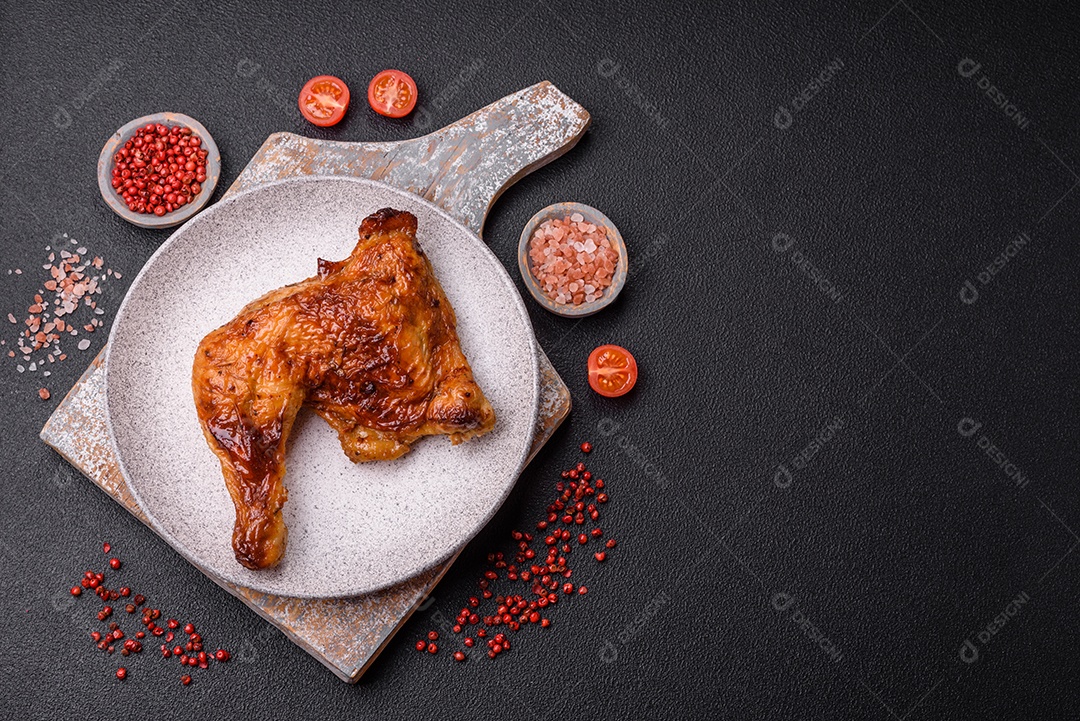 Deliciosa coxa ou quarto de frango grelhado com sal e especiarias em fundo escuro de concreto