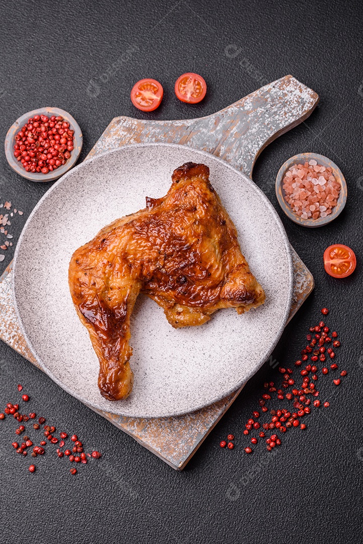 Deliciosa coxa ou quarto de frango grelhado com sal e especiarias em fundo escuro de concreto