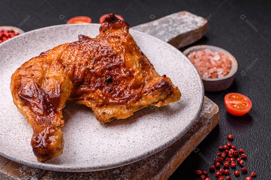 Deliciosa coxa ou quarto de frango grelhado com sal e especiarias em fundo escuro de concreto