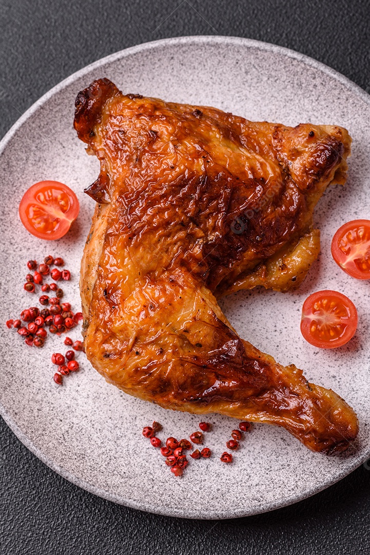 Deliciosa coxa ou quarto de frango grelhado com sal e especiarias em fundo escuro de concreto