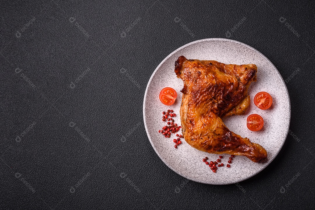 Deliciosa coxa ou quarto de frango grelhado com sal e especiarias em fundo escuro de concreto