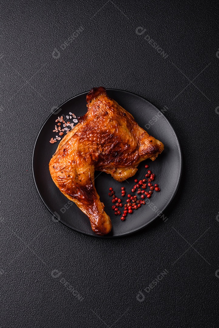 Deliciosa coxa ou quarto de frango grelhado com sal e especiarias em fundo escuro de concreto