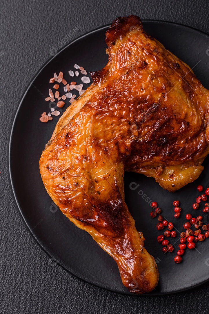 Deliciosa coxa ou quarto de frango grelhado com sal e especiarias em fundo escuro de concreto