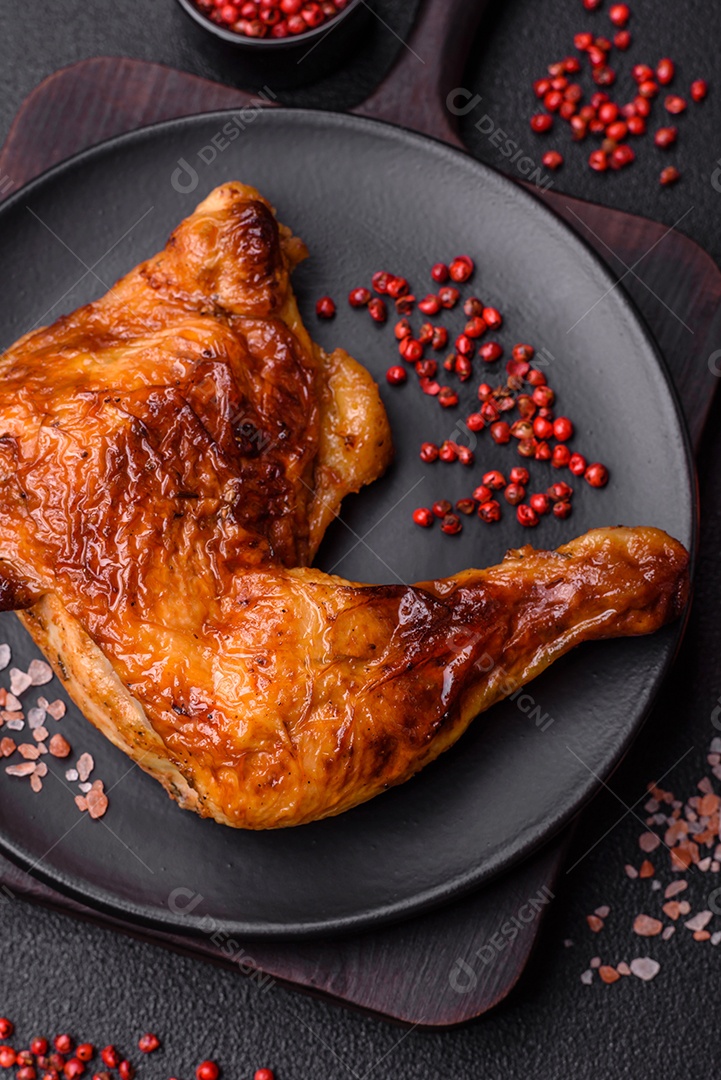 Deliciosa coxa ou quarto de frango grelhado com sal e especiarias em fundo escuro de concreto