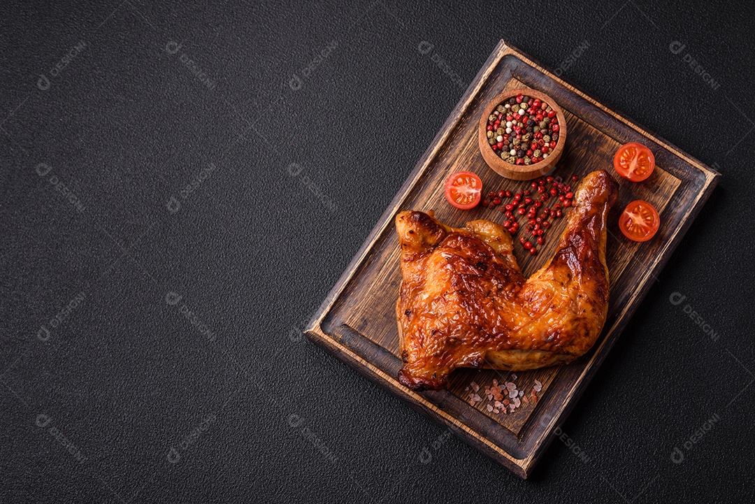 Deliciosa coxa ou quarto de frango grelhado com sal e especiarias em fundo escuro de concreto
