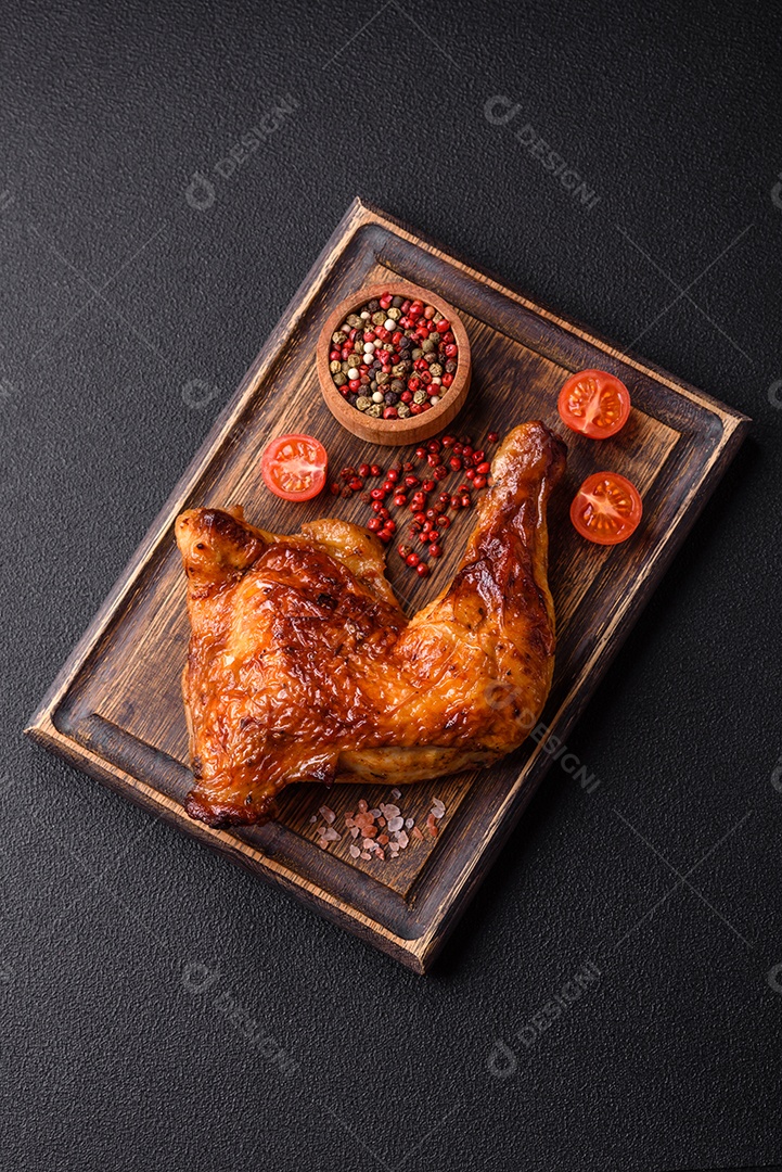 Deliciosa coxa ou quarto de frango grelhado com sal e especiarias em fundo escuro de concreto