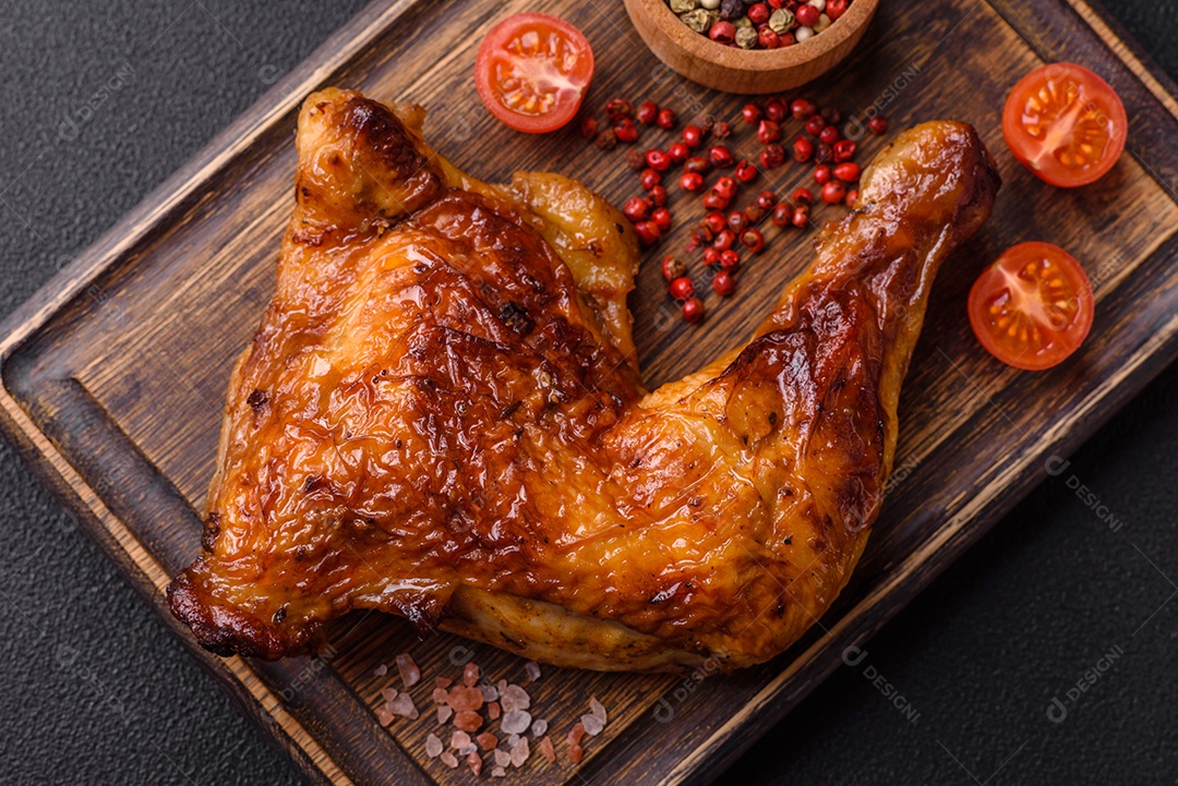 Deliciosa coxa ou quarto de frango grelhado com sal e especiarias em fundo escuro de concreto