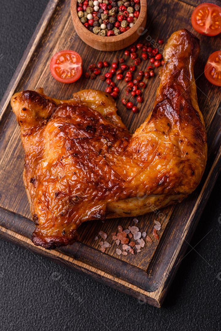 Deliciosa coxa ou quarto de frango grelhado com sal e especiarias em fundo escuro de concreto