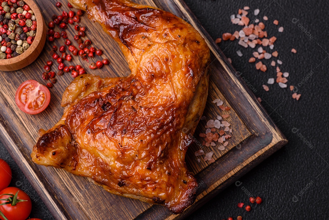 Deliciosa coxa ou quarto de frango grelhado com sal e especiarias em fundo escuro de concreto