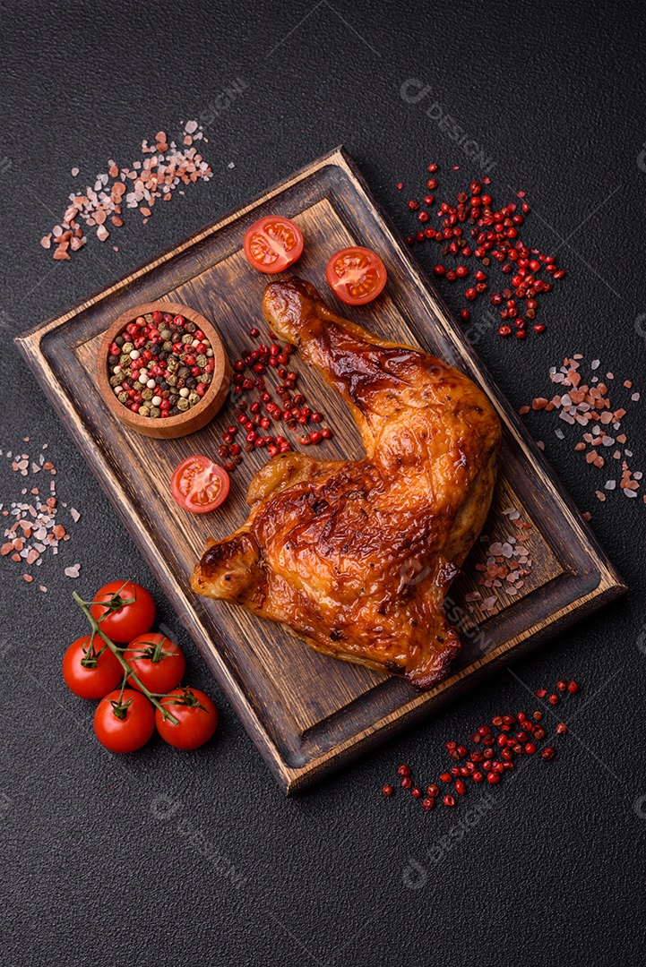 Deliciosa coxa ou quarto de frango grelhado com sal e especiarias em fundo escuro de concreto