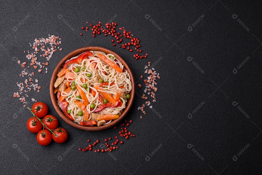 Delicioso macarrão de arroz ou udon com frango, cenoura, pimenta, sal, especiarias e ervas sobre fundo escuro de concreto