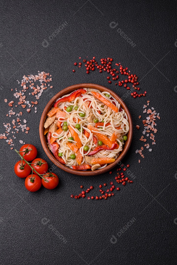 Delicioso macarrão de arroz ou udon com frango, cenoura, pimenta, sal, especiarias e ervas sobre fundo escuro de concreto