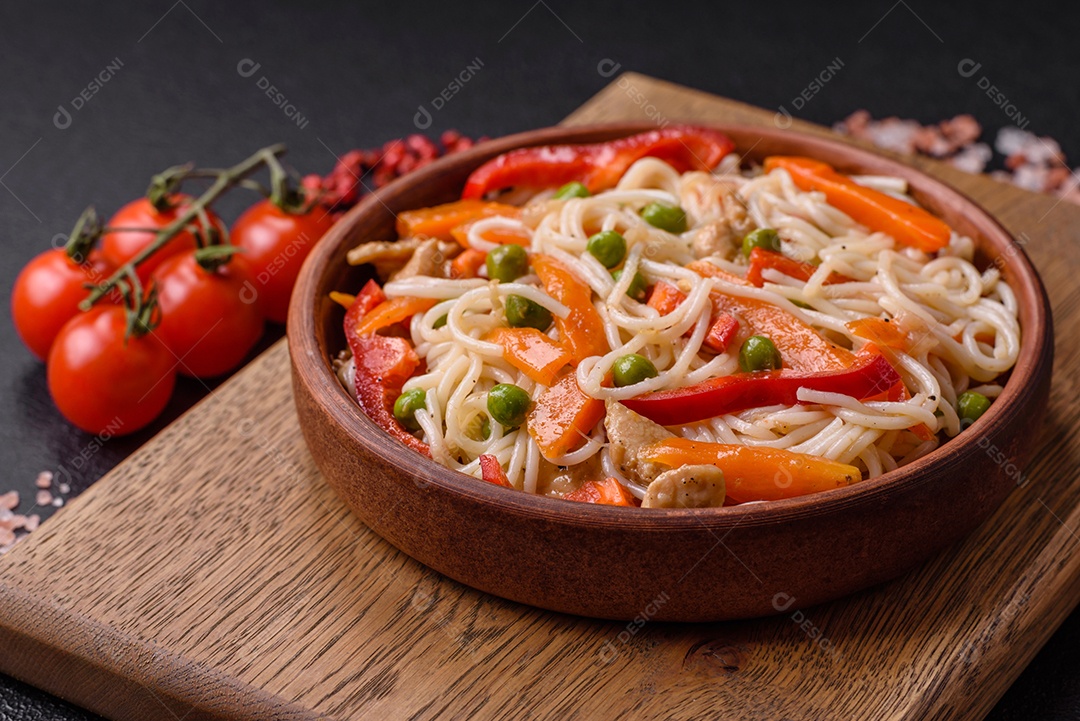 Delicioso macarrão de arroz ou udon com frango, cenoura, pimenta, sal, especiarias e ervas sobre fundo escuro de concreto