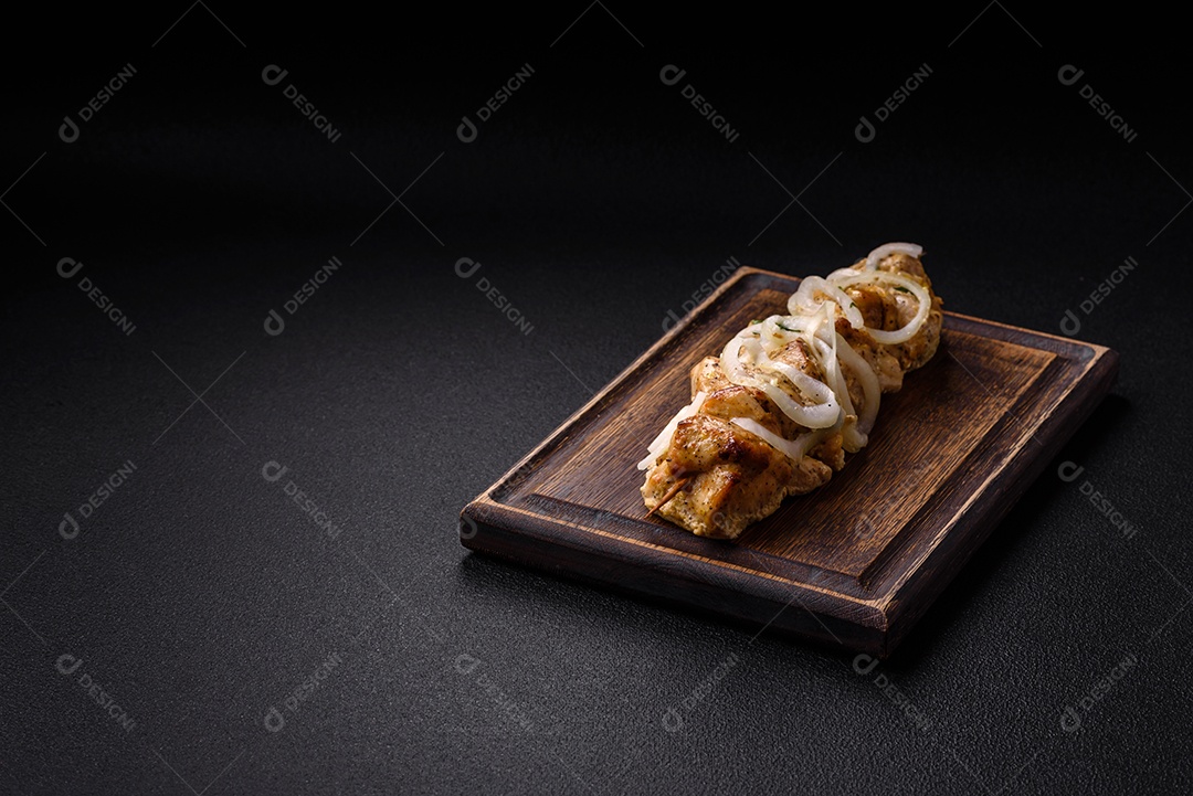 Delicioso kebab de carne de frango fresco com sal, especiarias e ervas sobre um fundo escuro de concreto