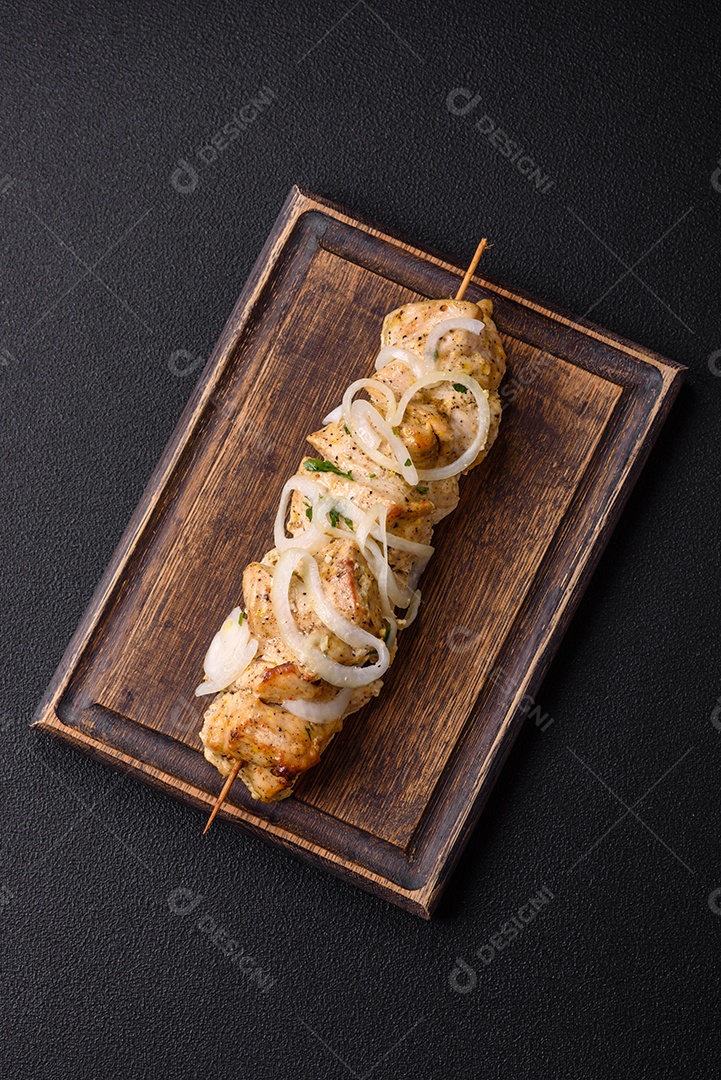 Delicioso kebab de carne de frango fresco com sal, especiarias e ervas sobre um fundo escuro de concreto