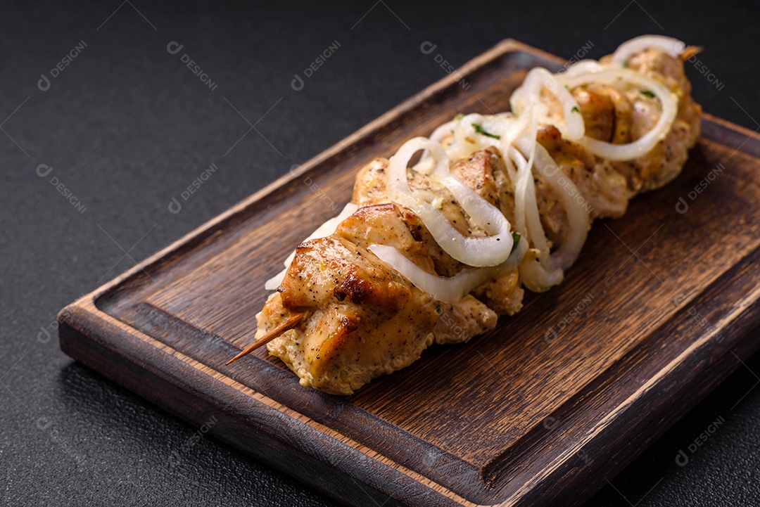 Delicioso kebab de carne de frango fresco com sal, especiarias e ervas sobre um fundo escuro de concreto