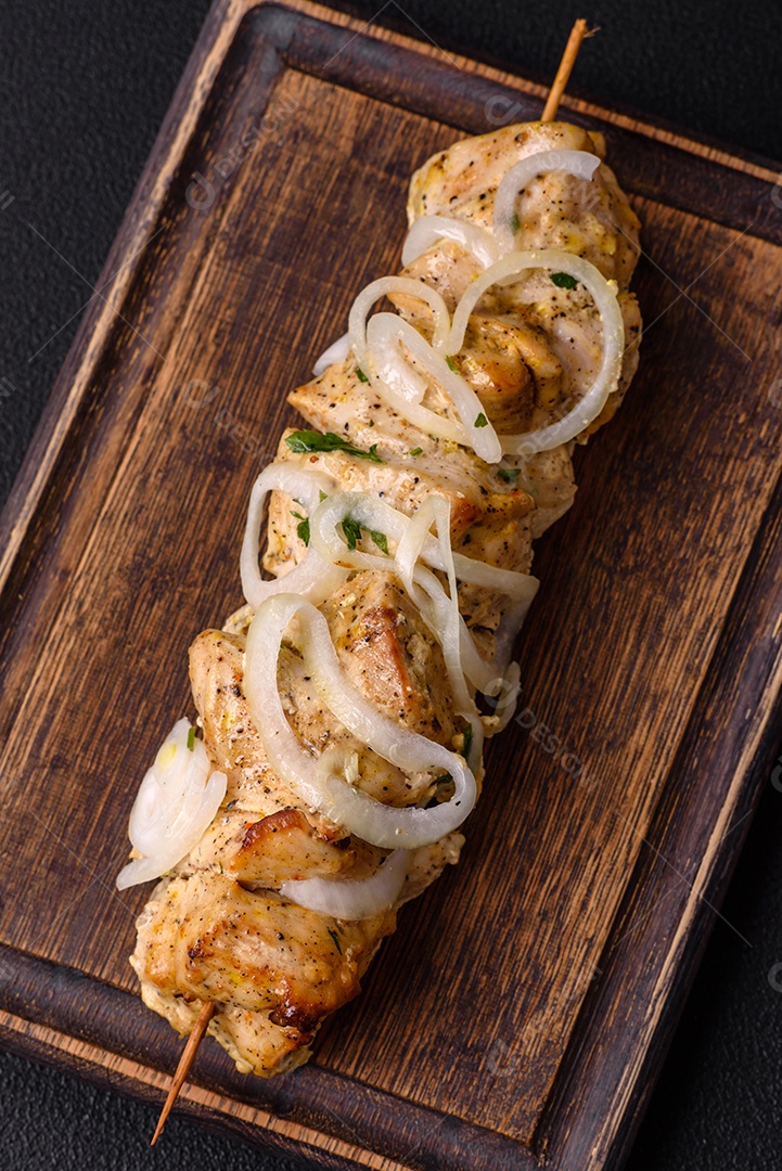 Delicioso kebab de carne de frango fresco com sal, especiarias e ervas sobre um fundo escuro de concreto
