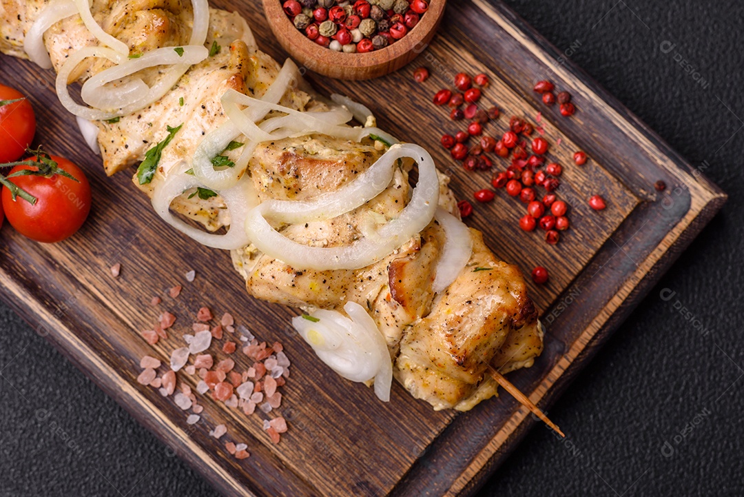 Delicioso kebab de carne de frango fresco com sal, especiarias e ervas sobre um fundo escuro de concreto