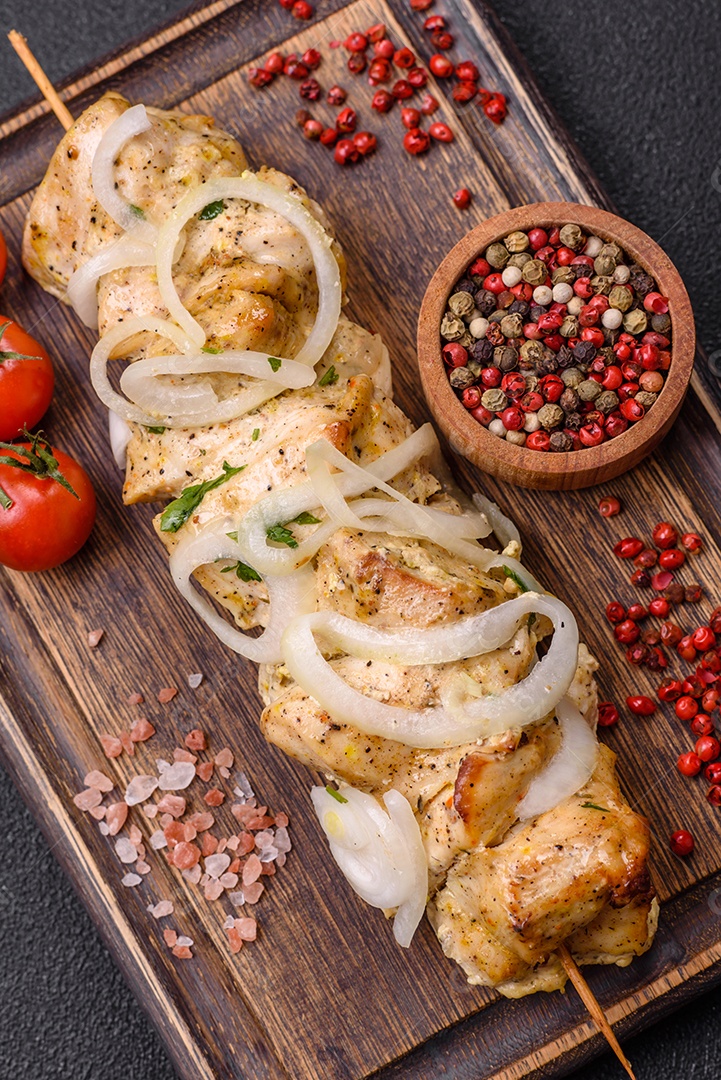Delicioso kebab de carne de frango fresco com sal, especiarias e ervas sobre um fundo escuro de concreto