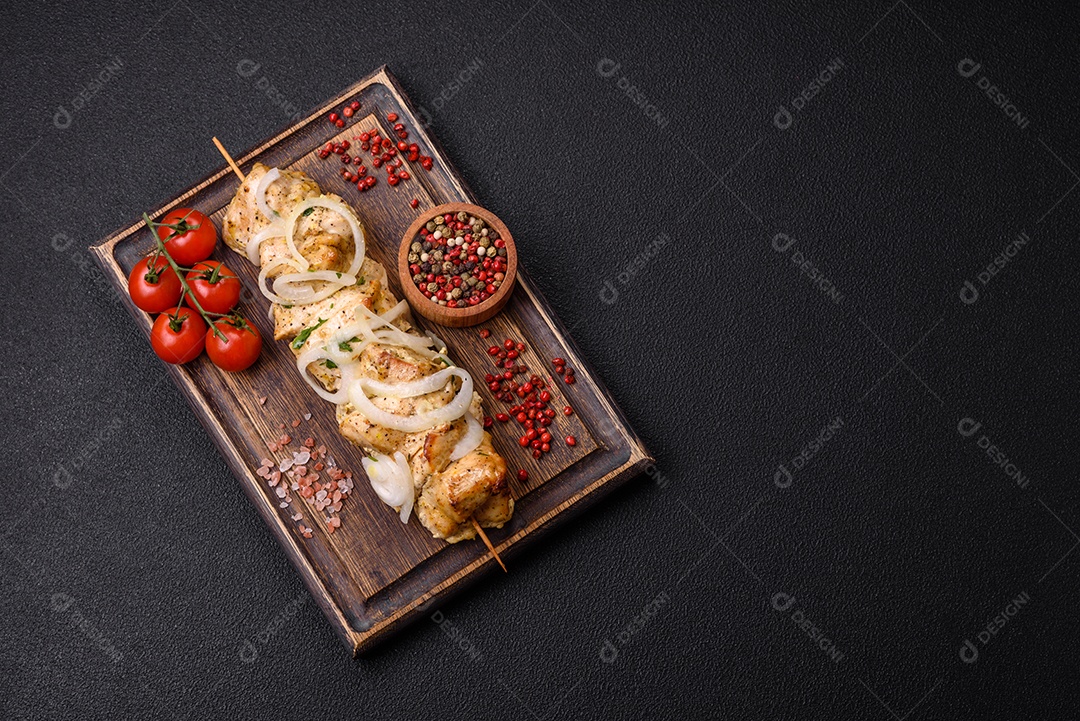 Delicioso kebab de carne de frango fresco com sal, especiarias e ervas sobre um fundo escuro de concreto