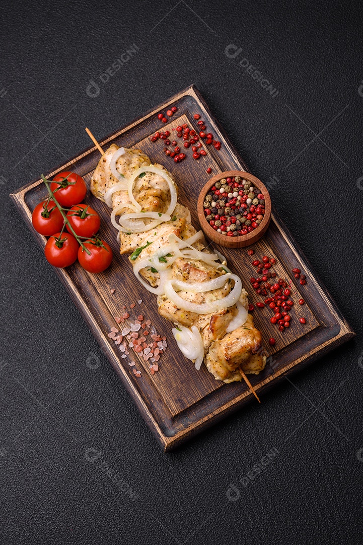 Delicioso kebab de carne de frango fresco com sal, especiarias e ervas sobre um fundo escuro de concreto