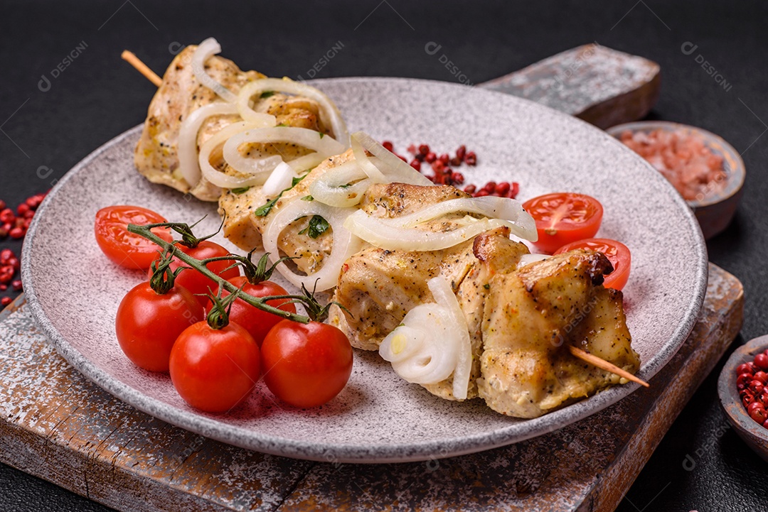Delicioso kebab de carne de frango fresco com sal, especiarias e ervas sobre um fundo escuro de concreto