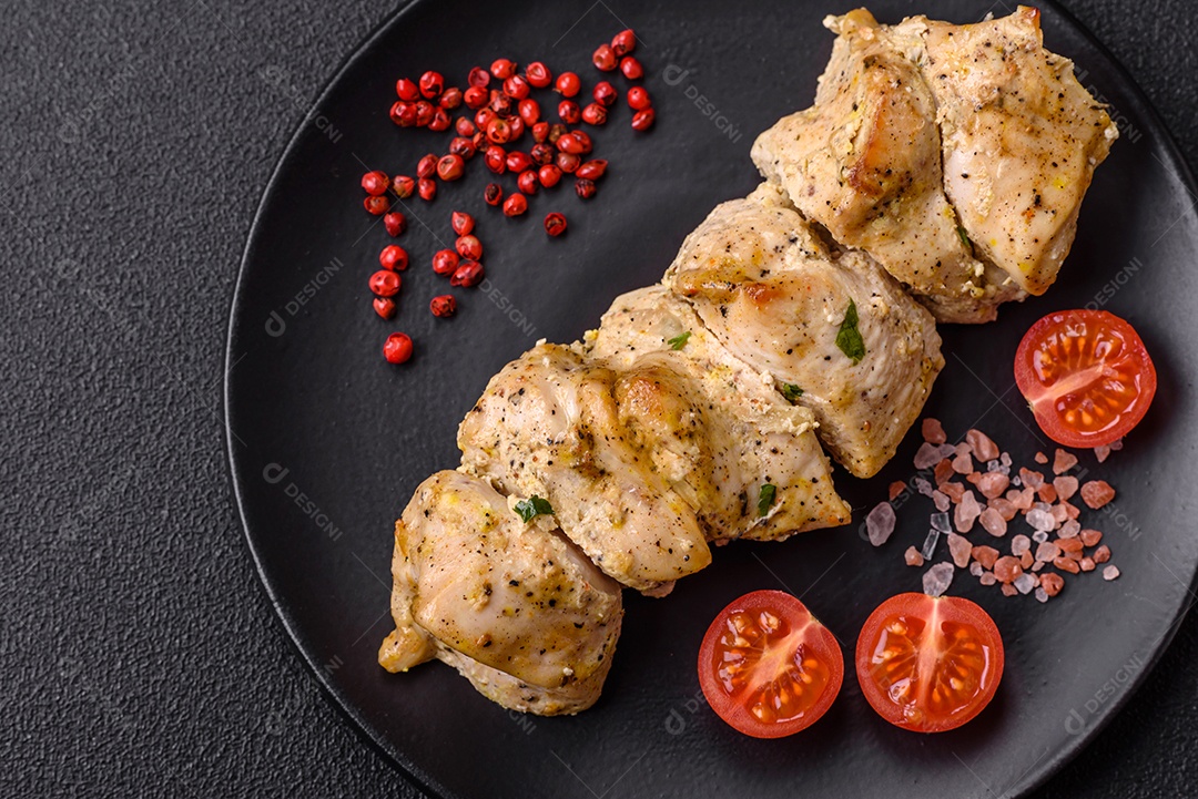 Delicioso kebab de carne de frango fresco com sal, especiarias e ervas sobre um fundo escuro de concreto