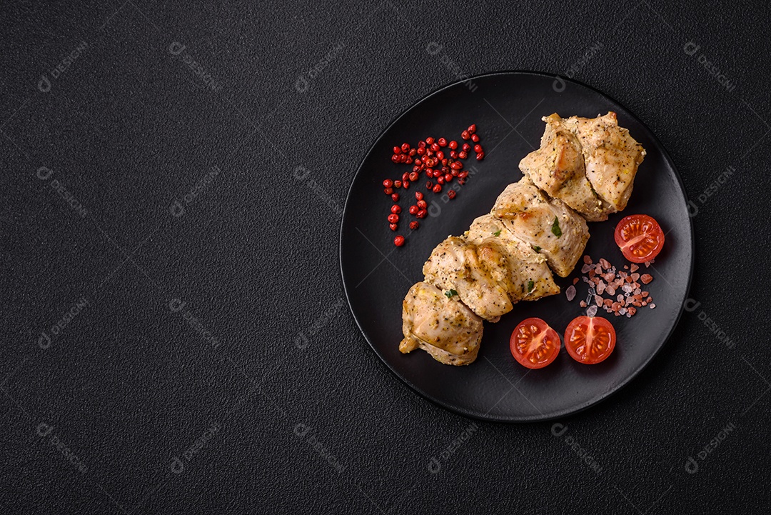 Delicioso kebab de carne de frango fresco com sal, especiarias e ervas sobre um fundo escuro de concreto